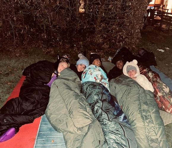 Five people together outside in sleeping bags.