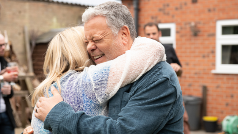 Man hugging a woman at a garden party.