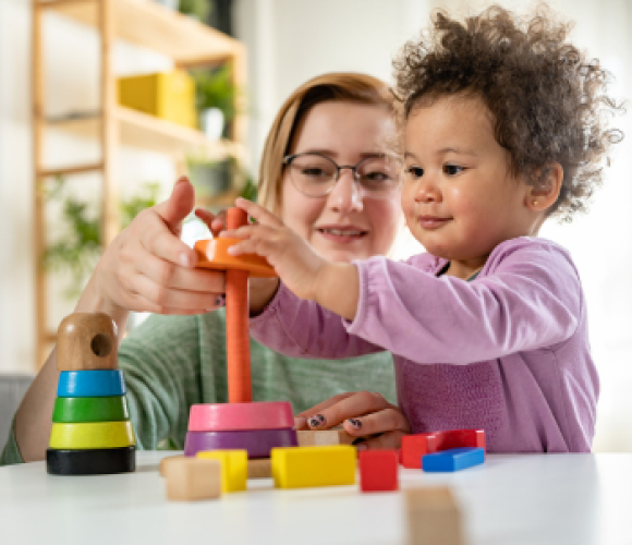 Image shows a women and a child stacking different coloured rings on top of each other.