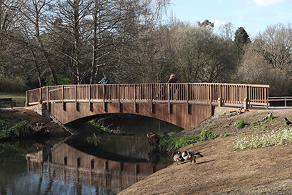 The new footbridge Kelsey Park new footbridge over a stream with pedestrians.