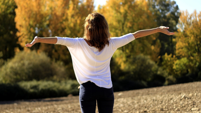 Woman outside with arms spread out.